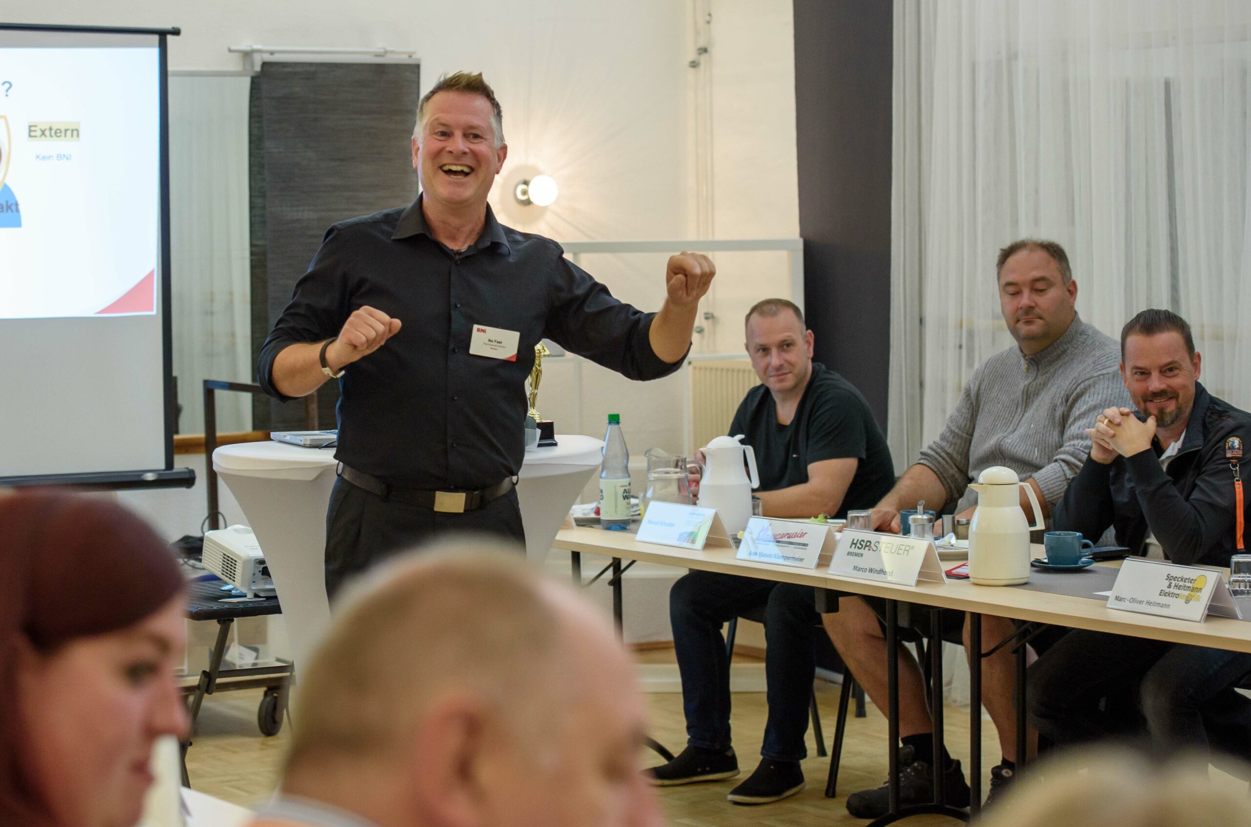 Rhetoriktrainer Ike Fast mit breitem Lächeln lehrt aktives Zuhören vor interessierten Zuhörern im Raum.