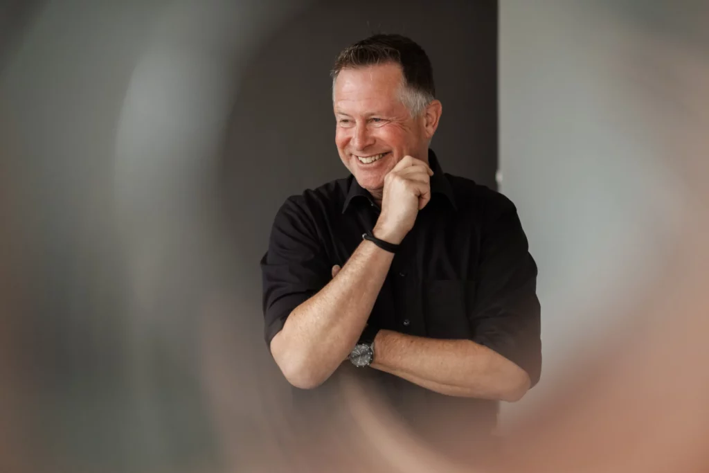 Redner Coach Ike Fast mit Hand an der Wange, lächelt an Kamera vorbei, faszinierender Zoom-Effekt.