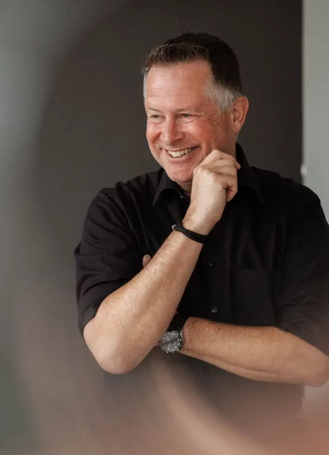 Redner Coach Ike Fast mit Hand an der Wange, lächelt an Kamera vorbei, faszinierender Zoom-Effekt.