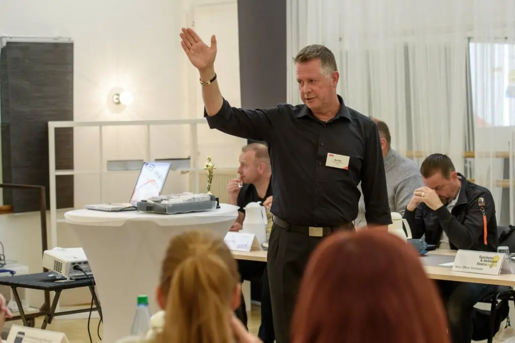 Rhetoriktrainer Ike Fast mit erhobener Hand zeigt etwas während er eine Präsentation hält.