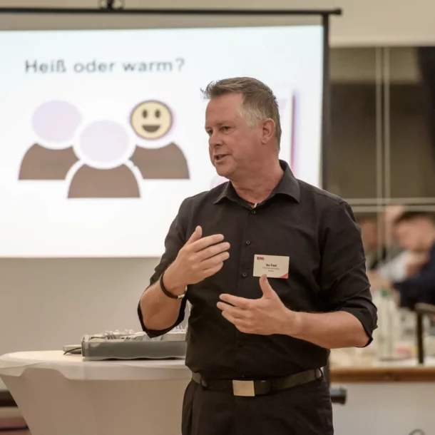 Rhetoriktrainer Ike Fast beantwortet Seminarfrage, vor Projektorpräsentation stehend.