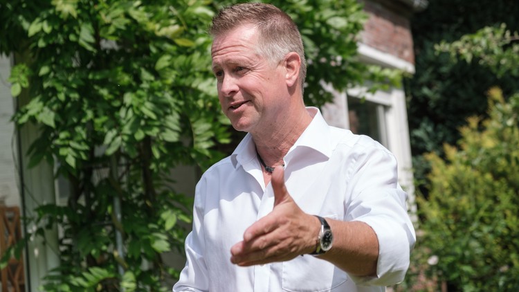 Ein Bild von Rhetoriktrainer Ike Fast mit Grünpflanzen im Hintergrund.